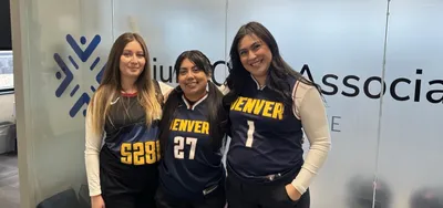 Three ICA team members in Denver Nuggets jerseys in front of the Injury Care Associates logo