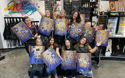 ICA team members holding up their canvases at a team paint night